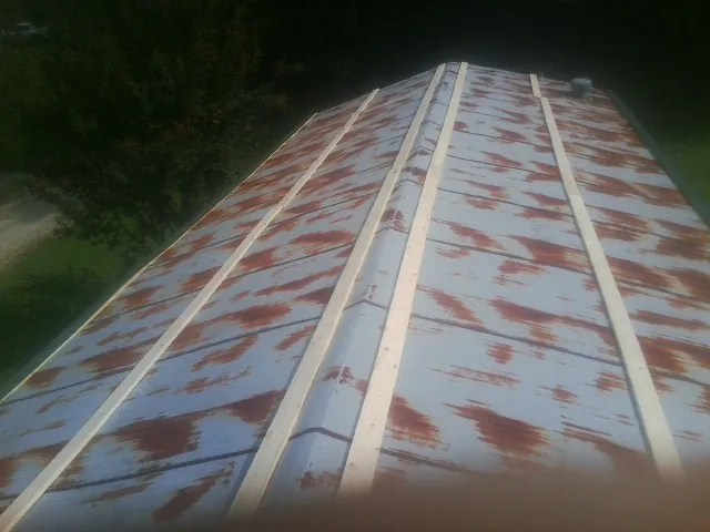 Rusted metal roof panels with new wood purlins before replacement — Storm Damage Roof Repair in North Webster by Roofing Brothers