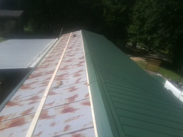Old rusted panels beside newly installed green metal roofing — Wind Damage Roof Repair by Roofing Brothers in North Webster
