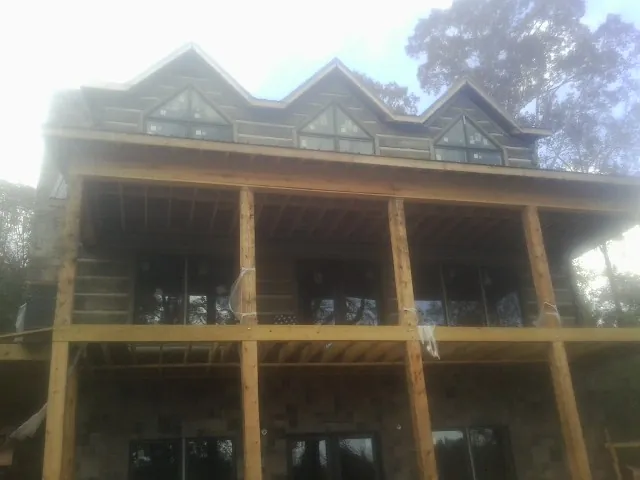 Dormers and porch framing on a large log home under construction — Roof Coating work by our crew in North Webster