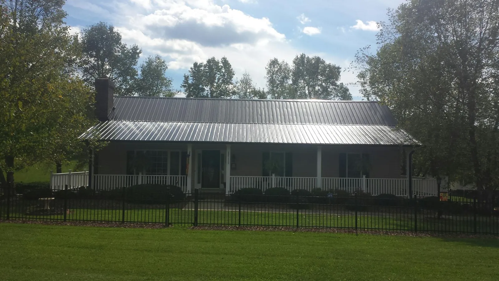 Gray metal roof on a brick ranch with a full width front porch — Gutter Guard Installation work by our crew in North Webster