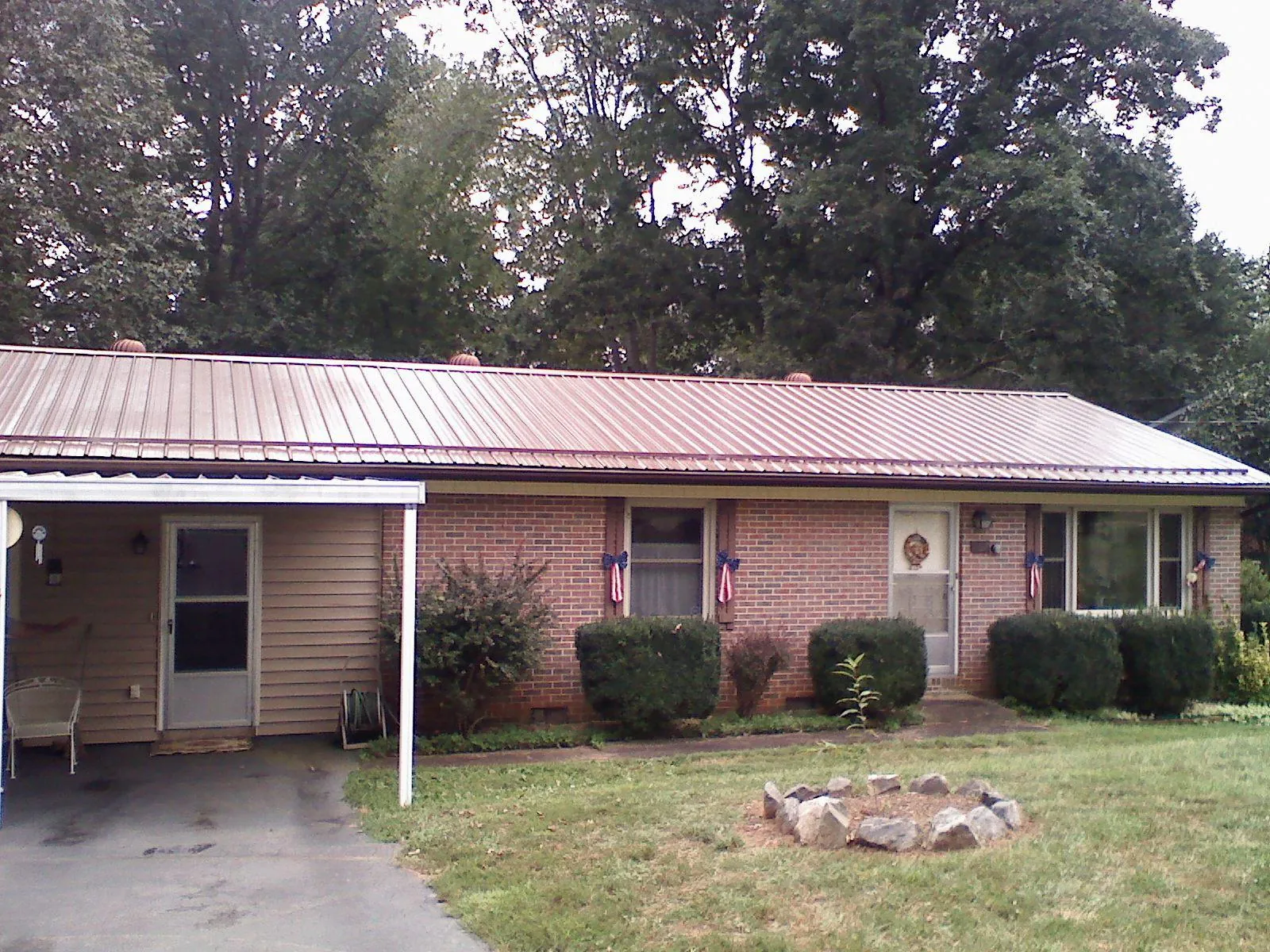 Bronze metal roof and carport on a brick ranch home — Roof Repair work by our crew in North Webster