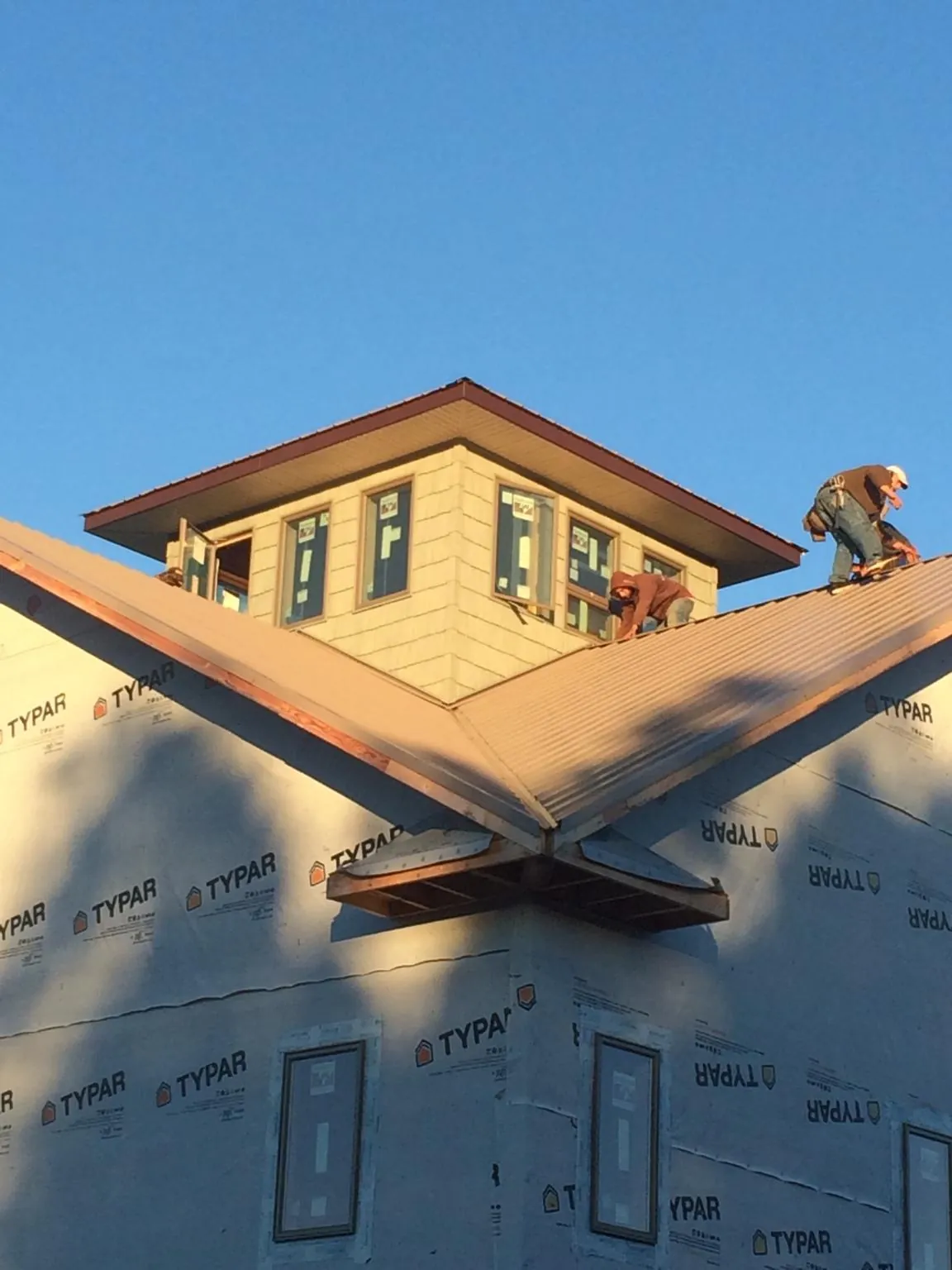 Roofers working around a rooftop cupola on a new metal roof at sunset — Roof Waterproofing in North Webster by Roofing Brothers